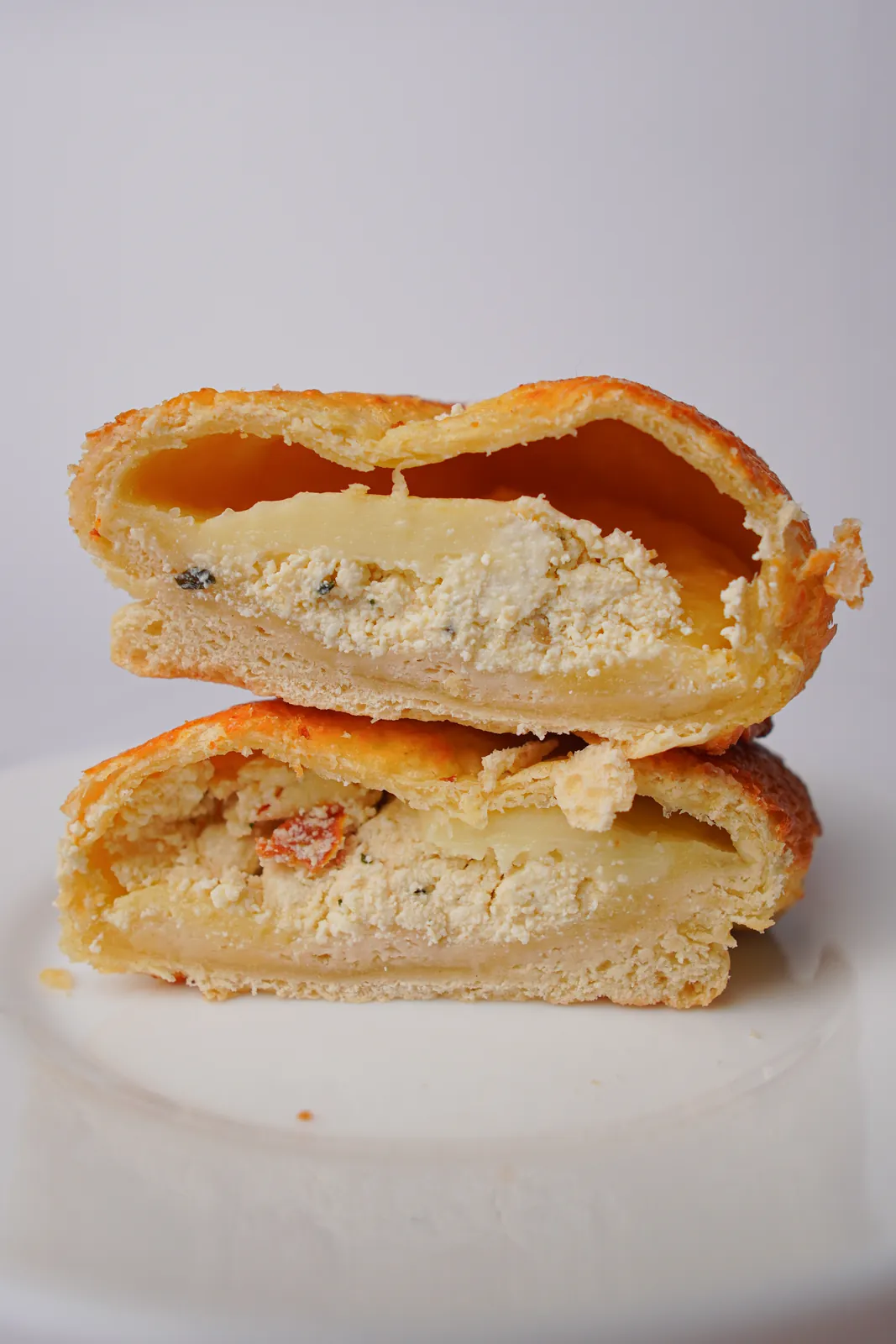 Assado três queijos no pão de leite aberto ao meio, num prato branco